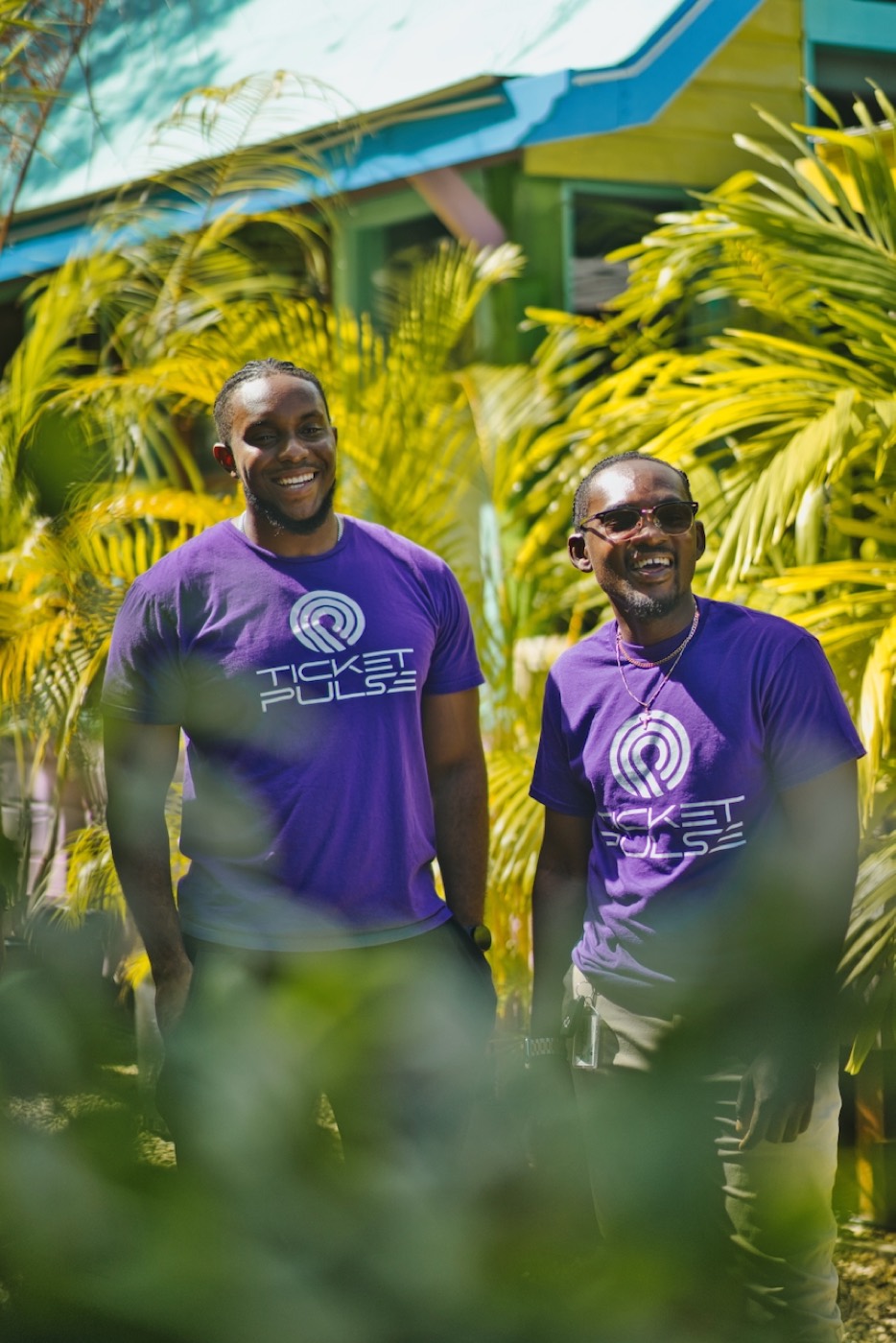 Two of the crew in TicketPulse shirts among palms.